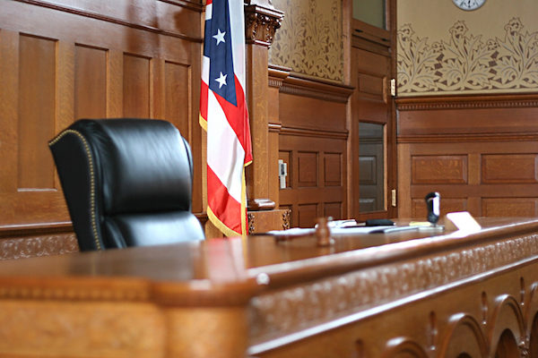 Empty judge’s bench next to an American flag in a United States courtroom.