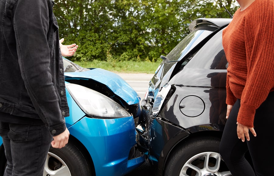 Two car owners talking in front of a rear-end car accident.